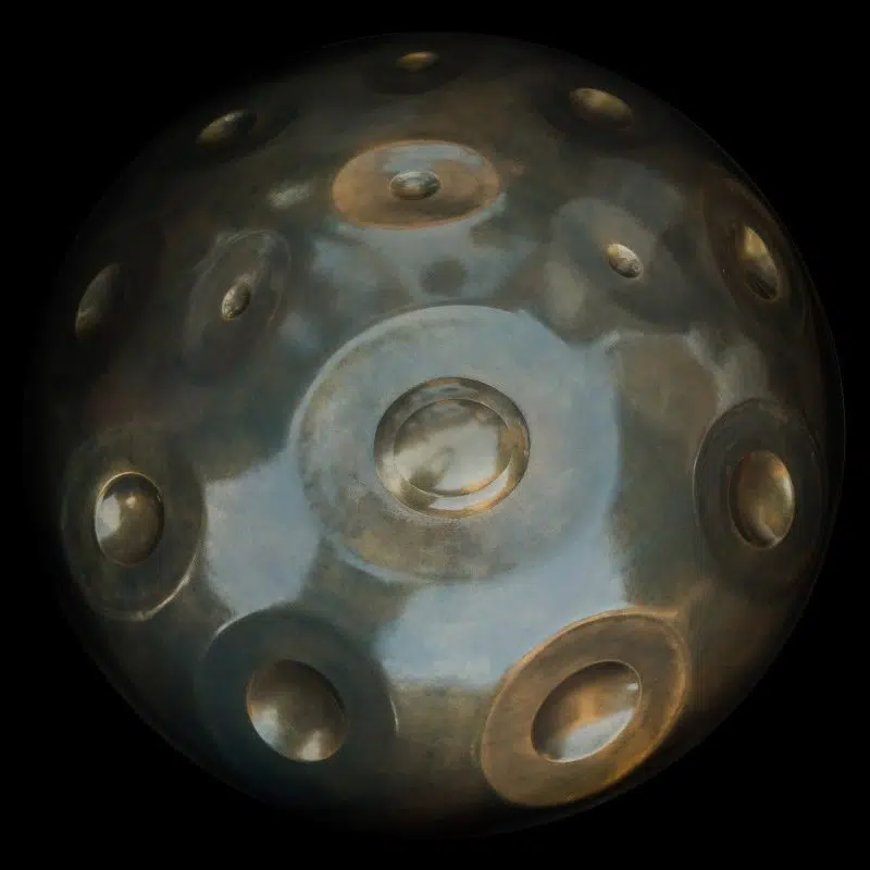 Handpan Yishama A Minor 17 vu de dessus sur fond noir : surface bleu-gris mouchetée de reflets bronze, le ding au centre et une quinzaine de zones de notes tout autour.